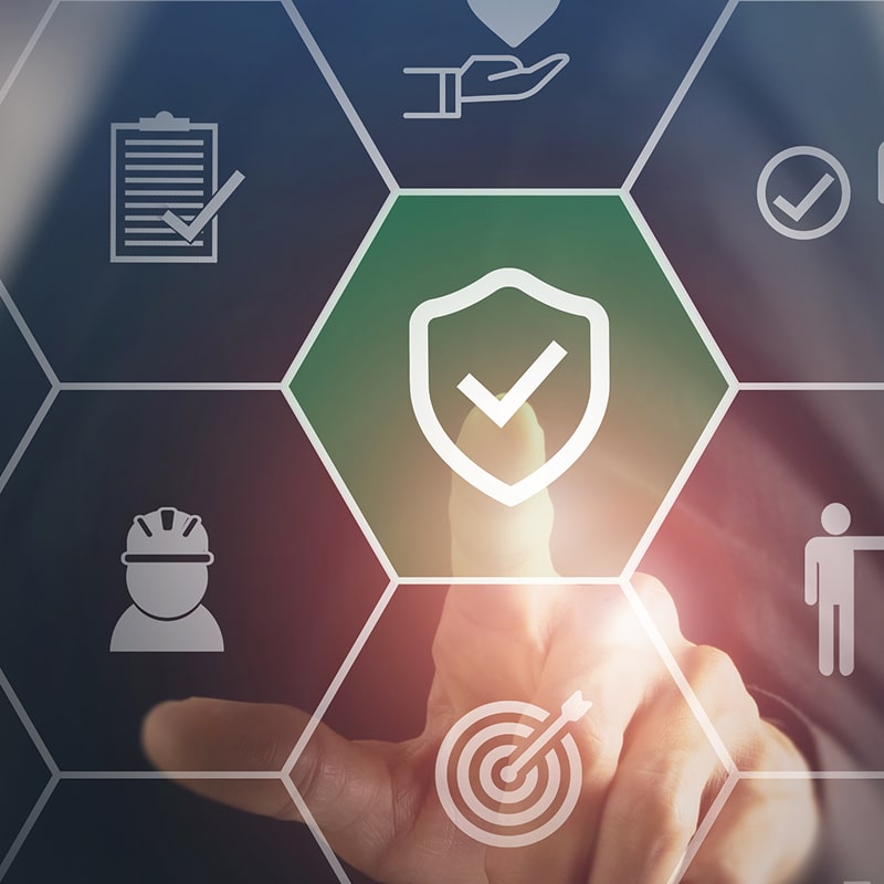 Sécurité digitale : protection, conformité et stratégie Main activant numériquement un bouclier de protection et sécurité, entouré d'icônes hexagonales de conformité, audit et stratégie de travail.